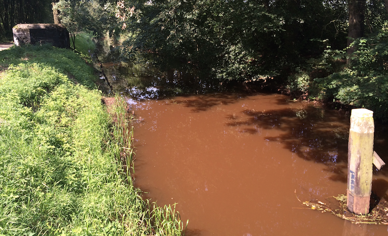 2014 cycling holiday photo: brown canal with a pillbox fortification